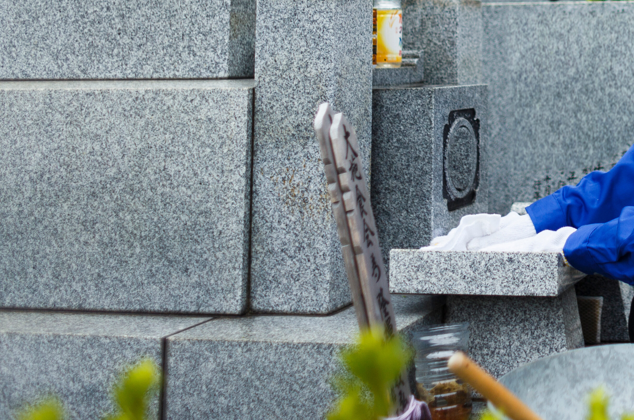 お墓掃除をする作業服の女性